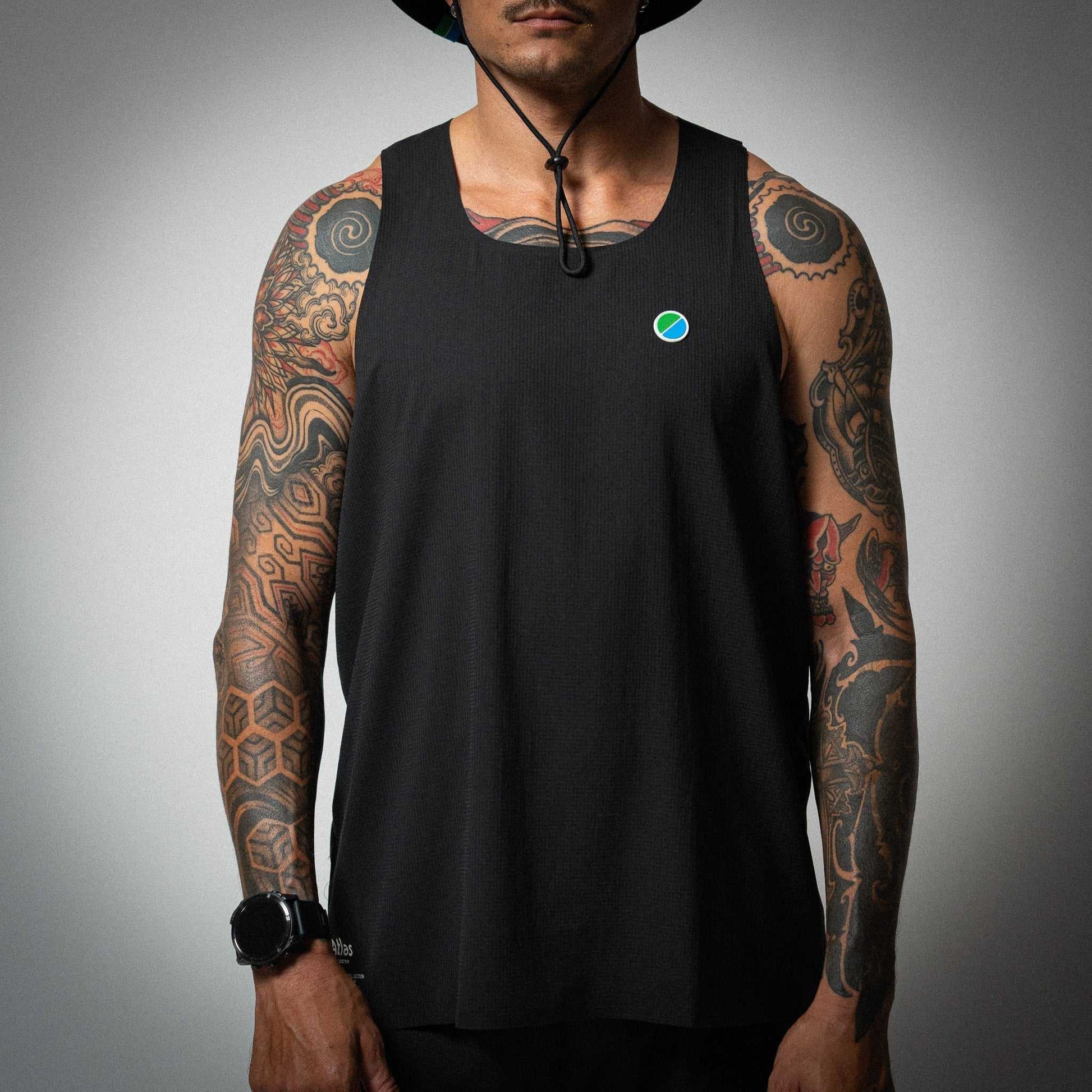 Aeria Fortis Race Tank in black worn by a model, showcasing breathable recycled ripstop fabric with silicone chest patch for runners.