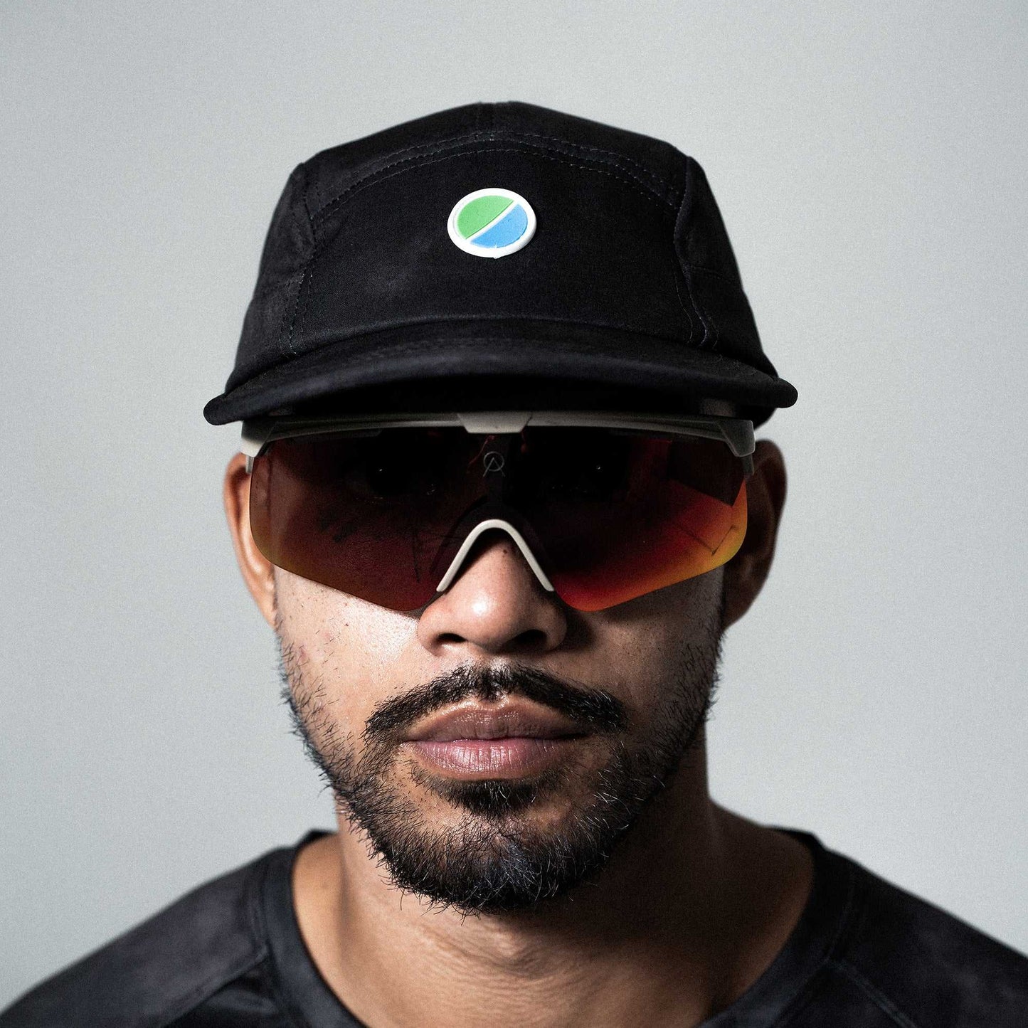 Black tie-dye running cap with logo, featuring lightweight, moisture-wicking polyester, adjustable strap, and reflective details.