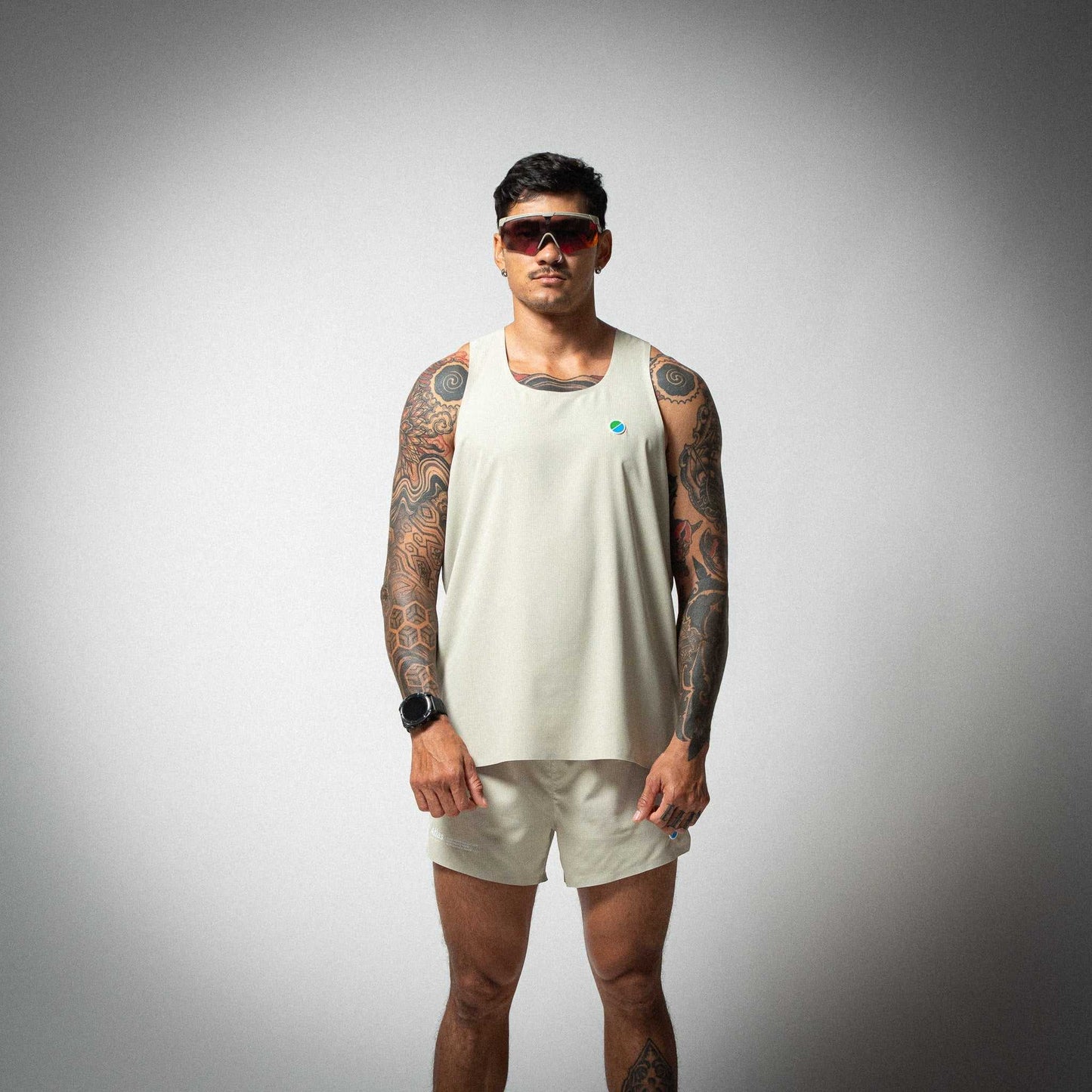 Aeria Fortis Race Tank Beige worn by male model, featuring lightweight breathable design with silicone chest patch.